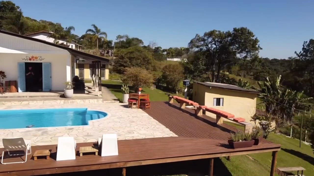 Drone sobre o deck de madeira e a piscina, com a casa e a edícula ao lado