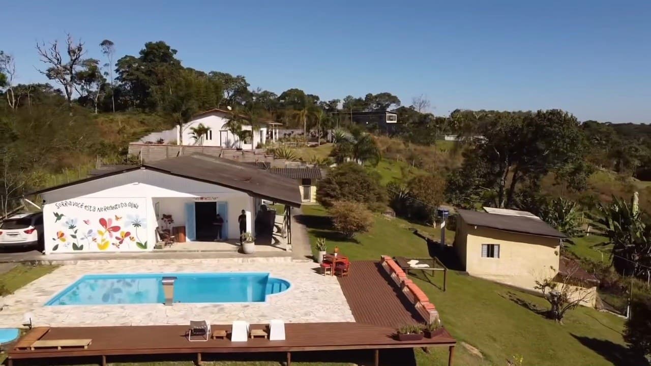 Vista aérea da casa com o mural de flores, a piscina, o deck de madeira e o gramado