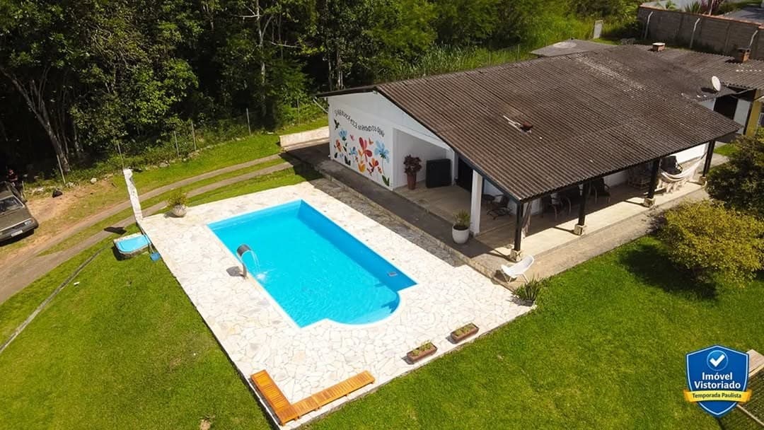 Vista aérea da casa, da piscina e do deck em meio ao gramado