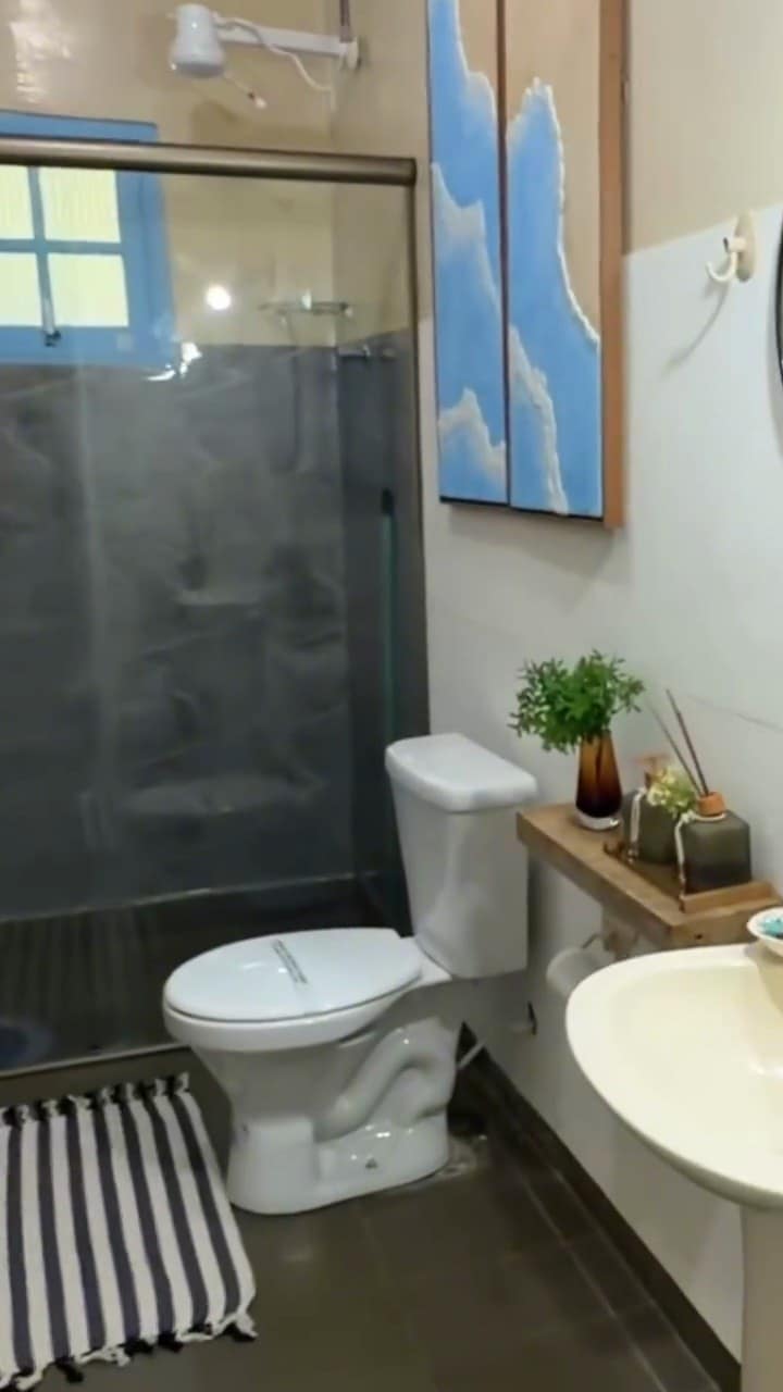 Banheiro com box de vidro e bancada com plantas