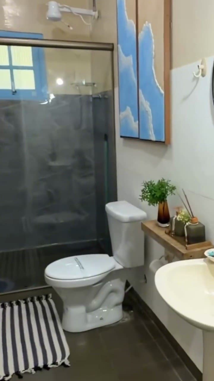 Banheiro com box de vidro e bancada com plantas