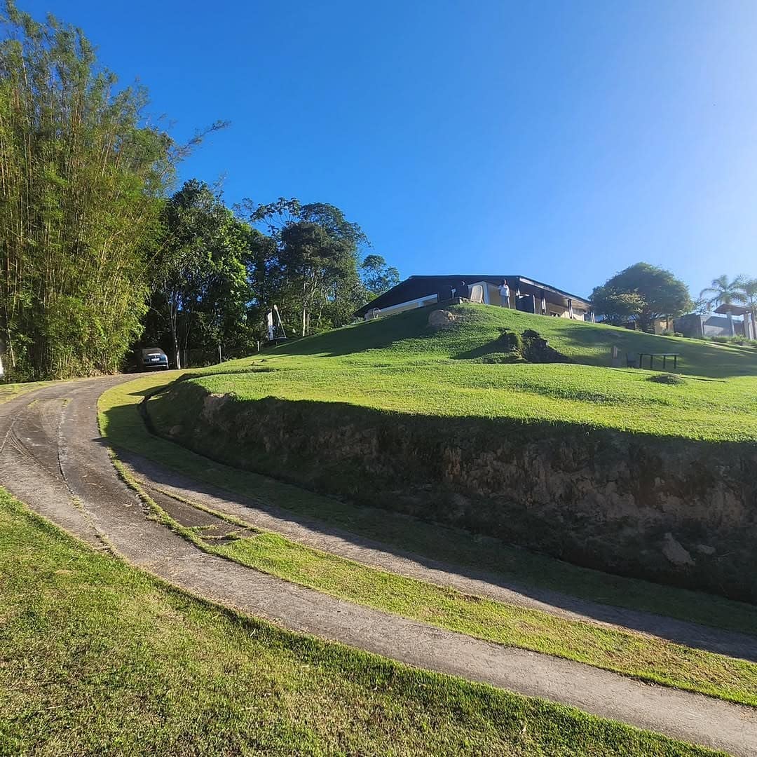 Estrada de terra subindo a colina até a casa no topo
