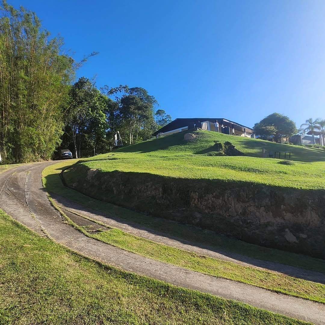 Estrada de terra subindo a colina até a casa no topo