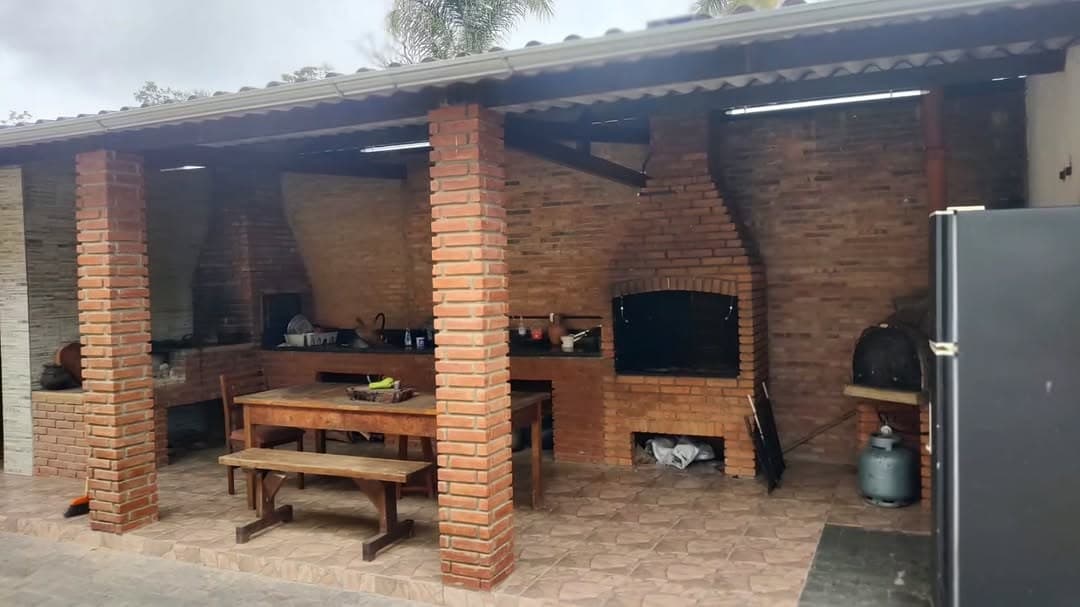 Churrasqueira e bancada de tijolos na área gourmet coberta