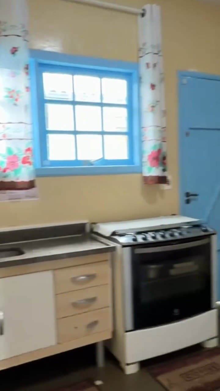 Cozinha com fogão, armários e janela azul
