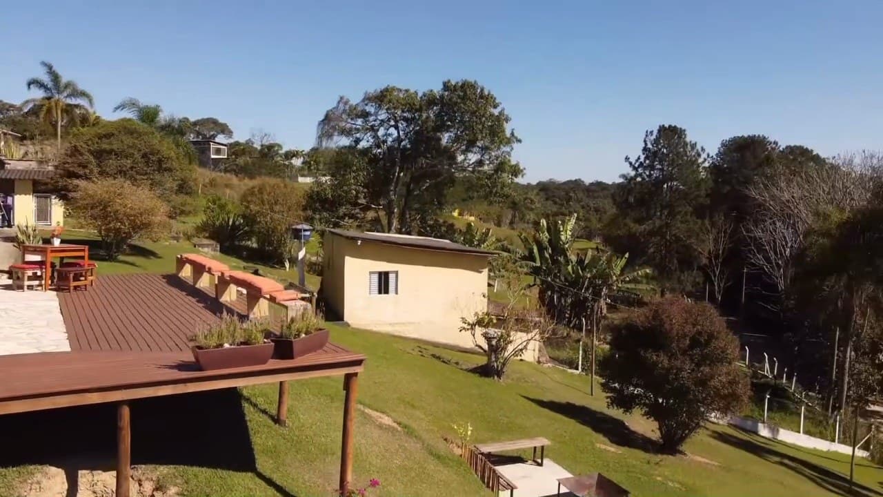 O deck de madeira elevado sobre o gramado, com floreiras e a edícula ao fundo
