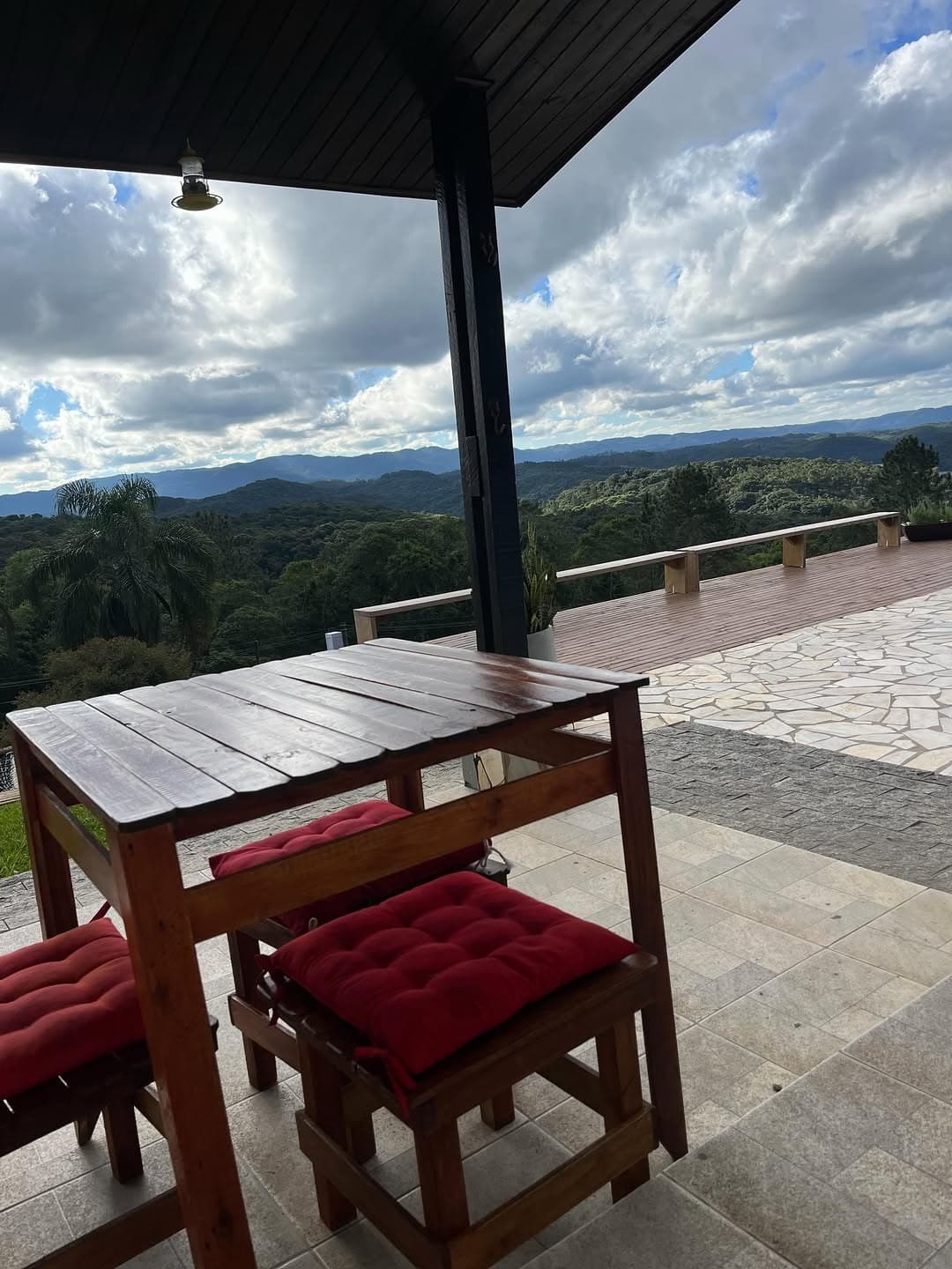 Mesa com almofadas vermelhas no deck, com vista para a serra