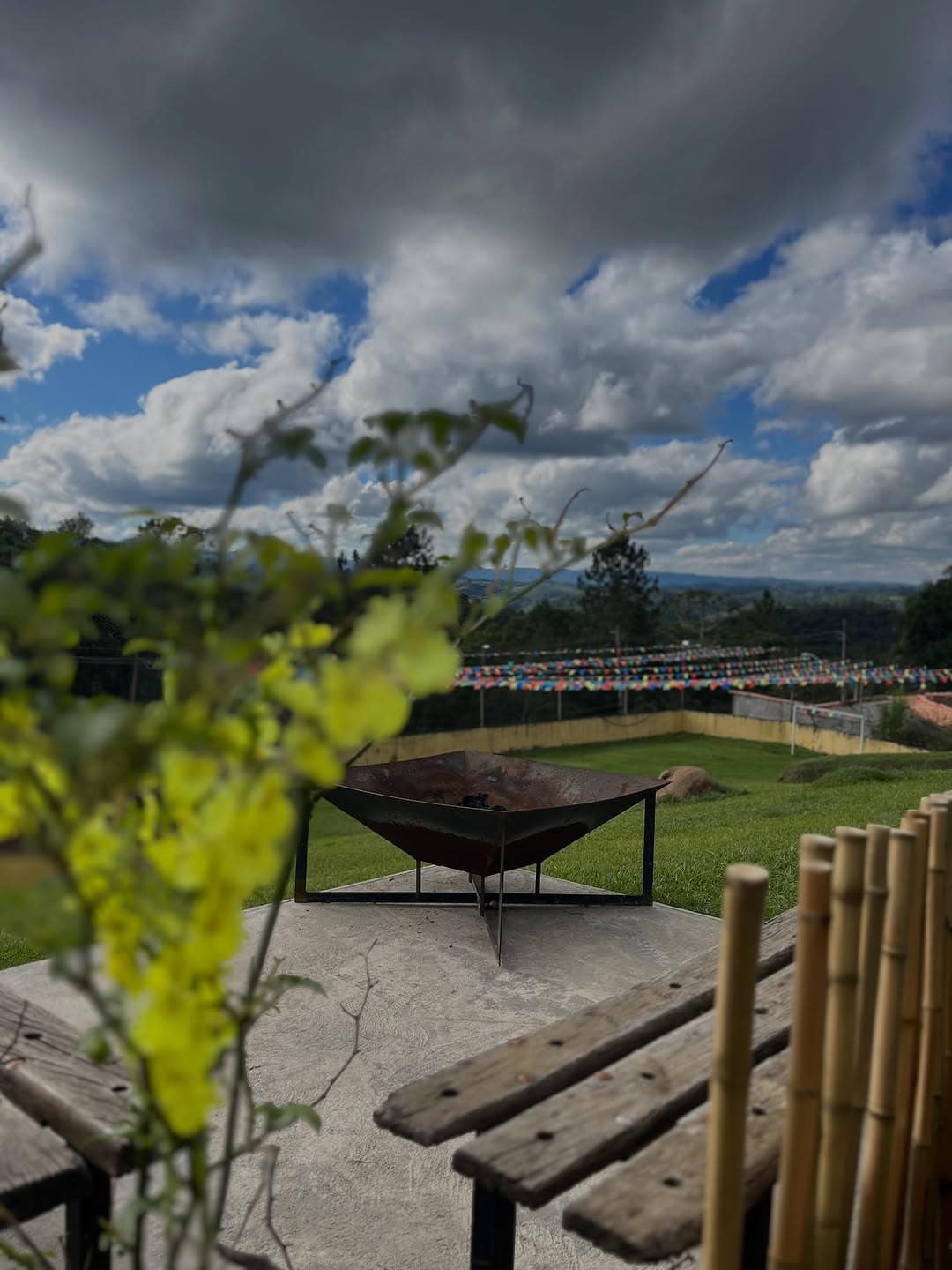 Espaço da fogueira com bancos de madeira, de frente para o campo e a serra