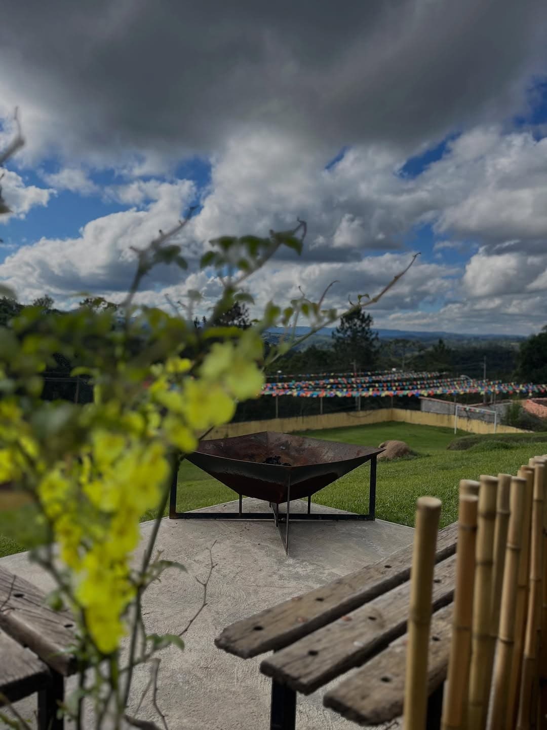 Espaço da fogueira com bancos de madeira, de frente para o campo e a serra