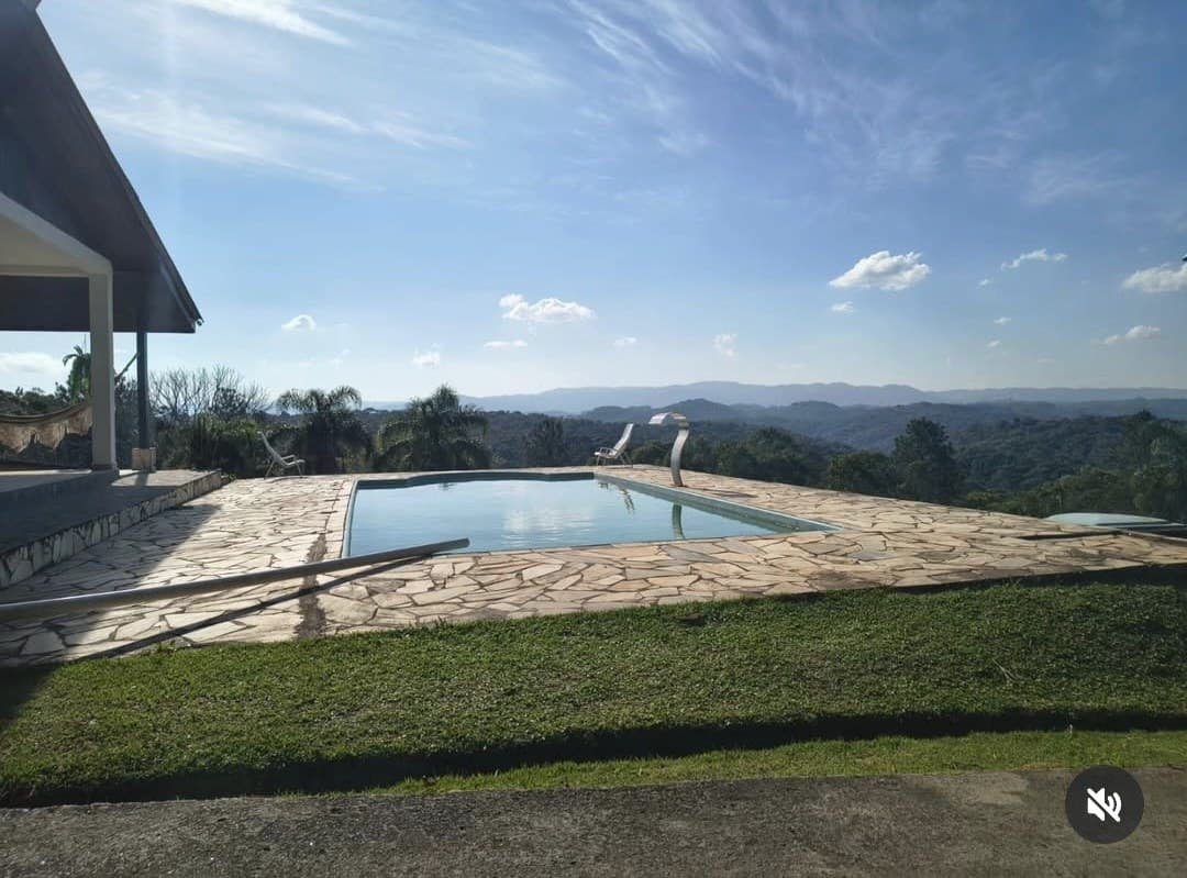 Piscina e deck ao lado da varanda, com a mata e as serras ao fundo