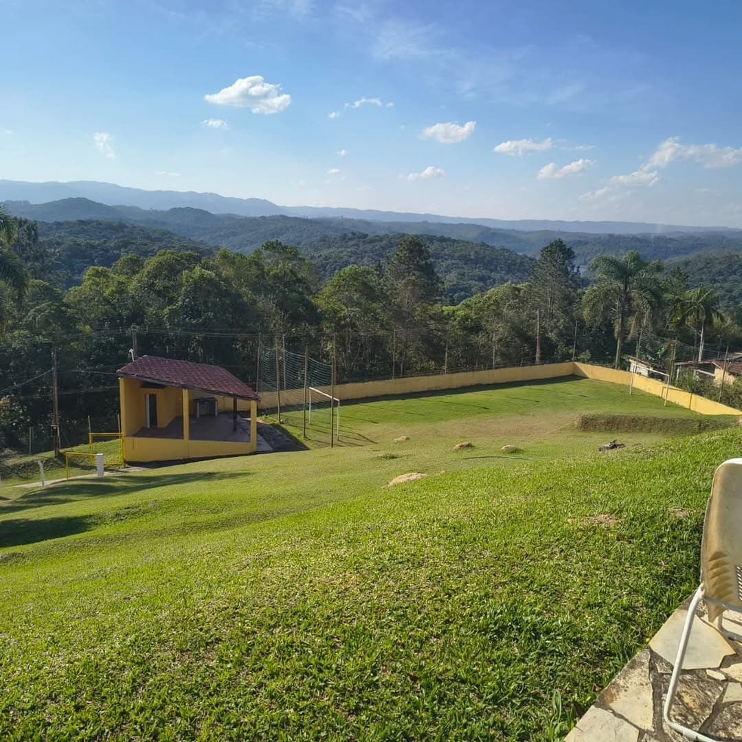 Gramado em declive com o campo de futebol e a edícula