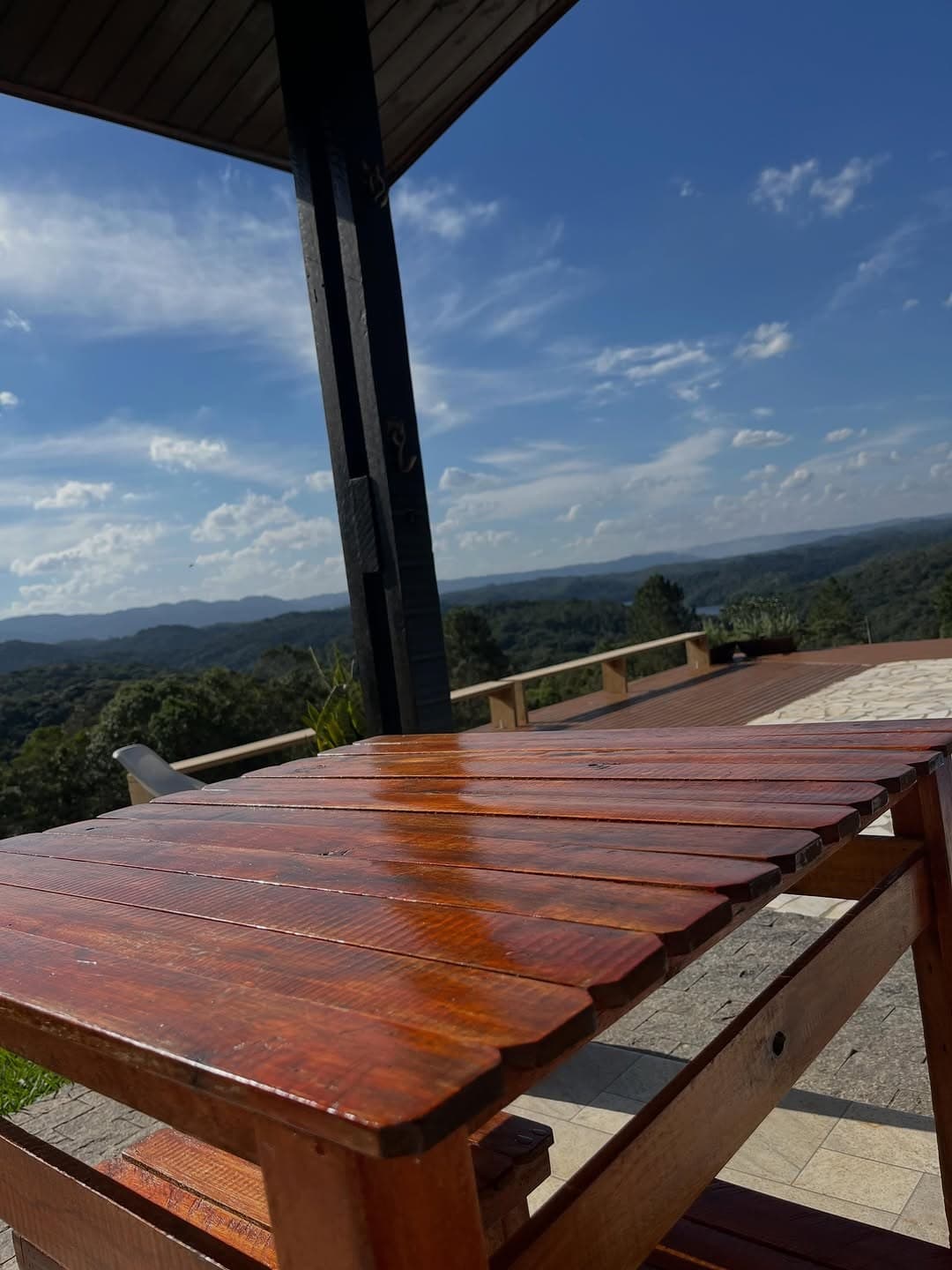 Mesa de madeira na varanda, com o deck e a vista das serras
