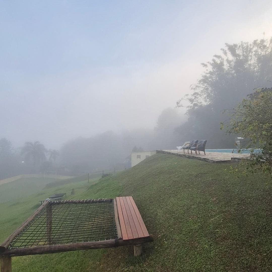 Manhã de neblina sobre a encosta, com a rede de descanso e o banco