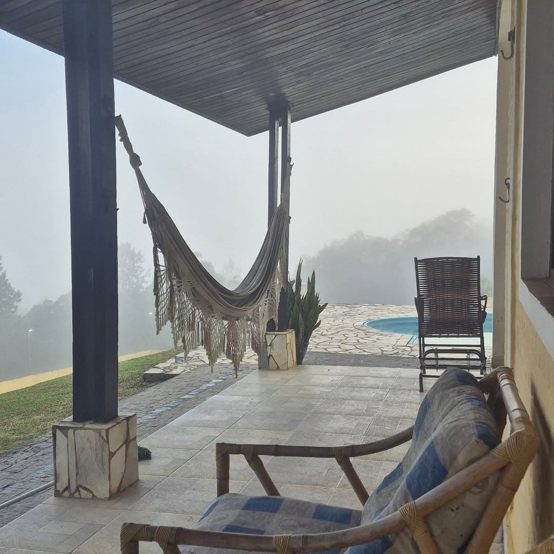 Varanda com rede e poltrona numa manhã de neblina