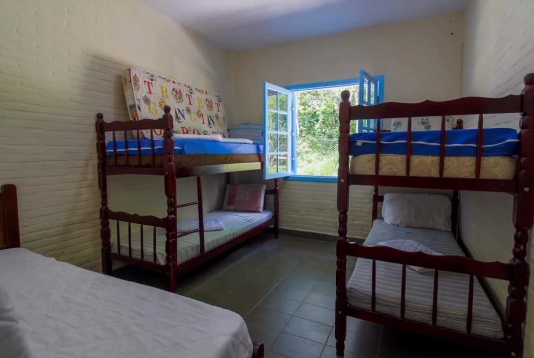Quarto com dois beliches, cama de solteiro e janela para o jardim