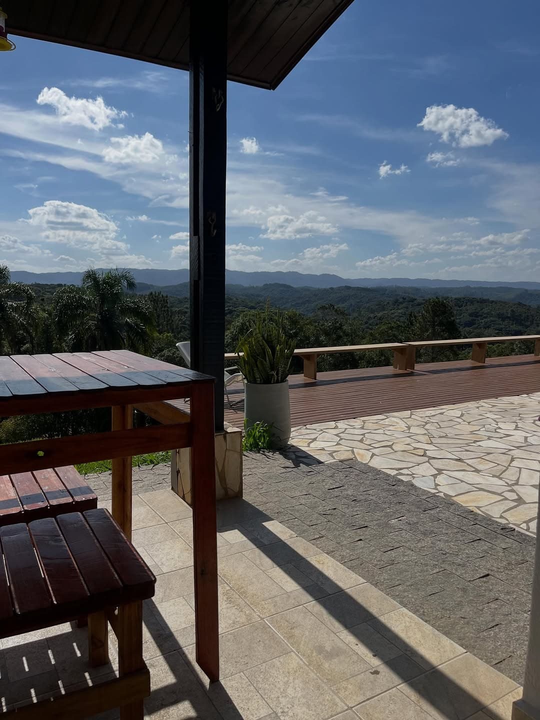 Mesa e bancos na varanda coberta, olhando para o deck e as montanhas