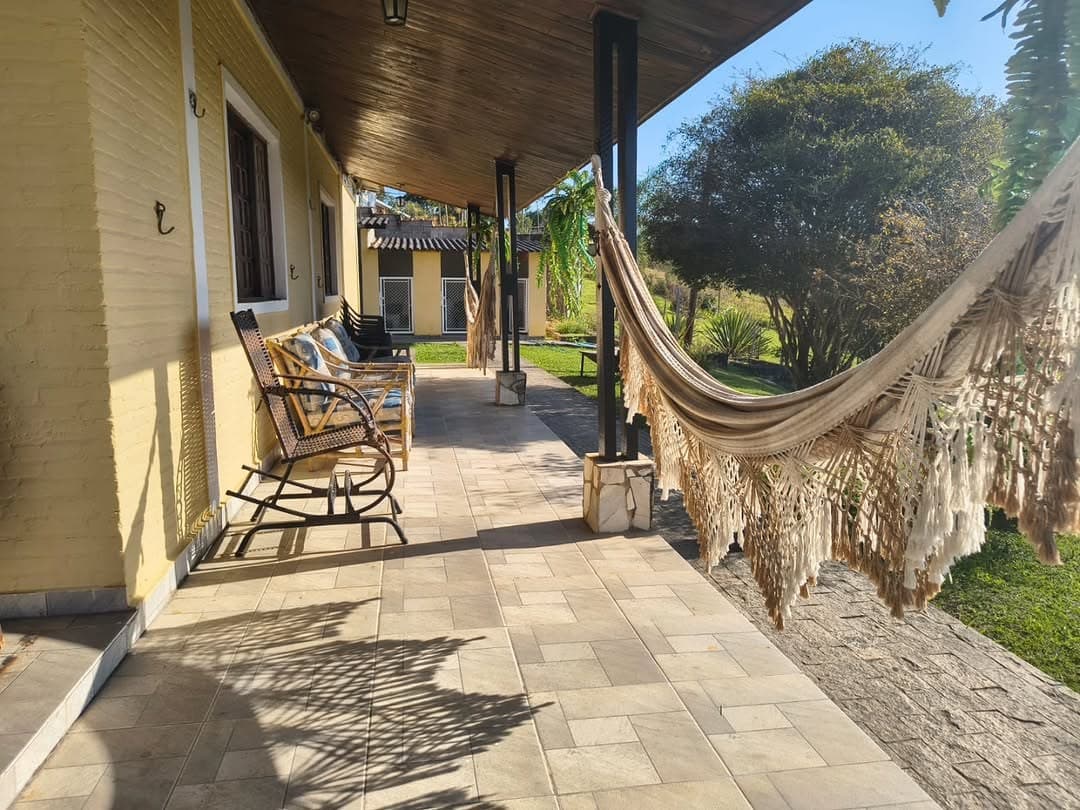 Varanda com rede, poltronas de balanço e o jardim ao fundo